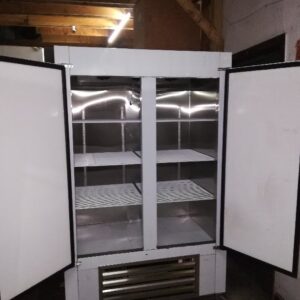 An Cooltech Stainless Steel 2-Door Reach-In Cooler 48” with empty shelves in a dimly lit storage room.